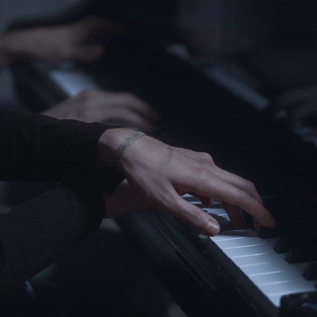Mains jouant du piano dans une lumière sombre